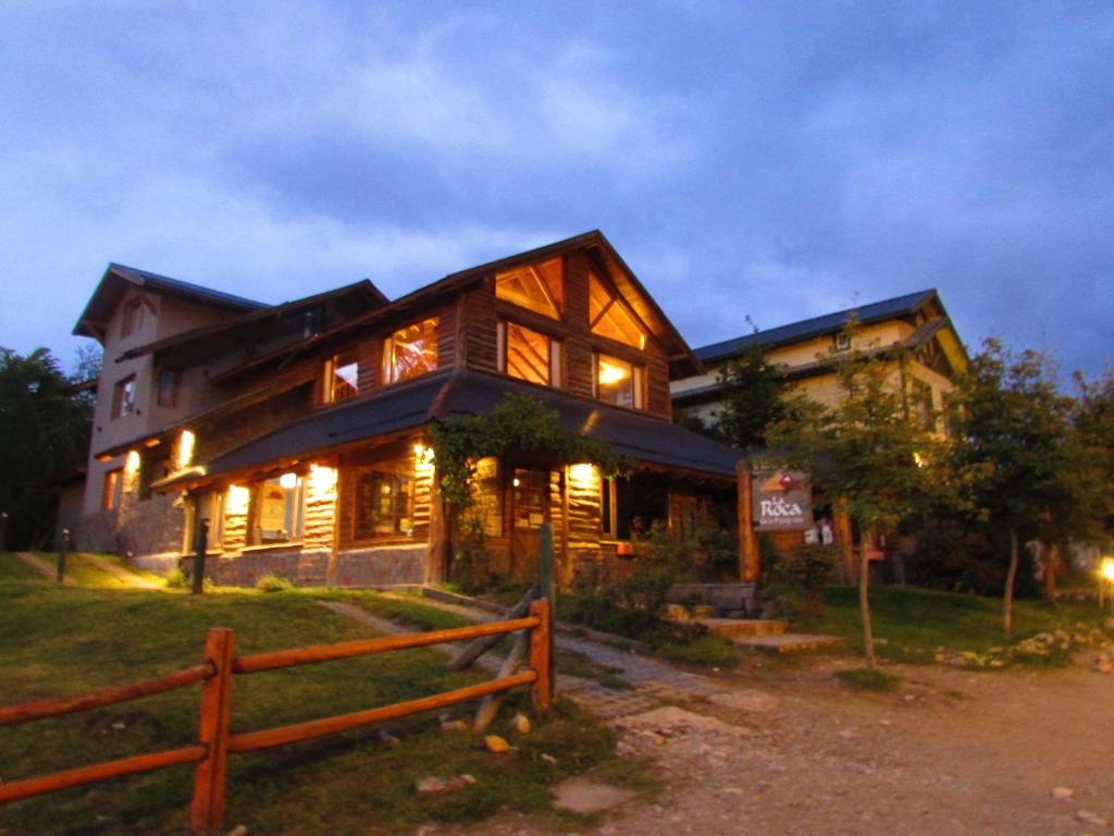 uma grande casa de madeira com uma cerca em frente em La Roca de la Patagonia em Villa La Angostura