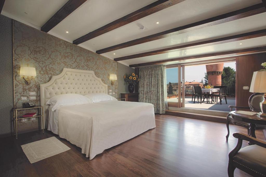 a bedroom with a white bed and a balcony at Hotel Santa Chiara in Venice