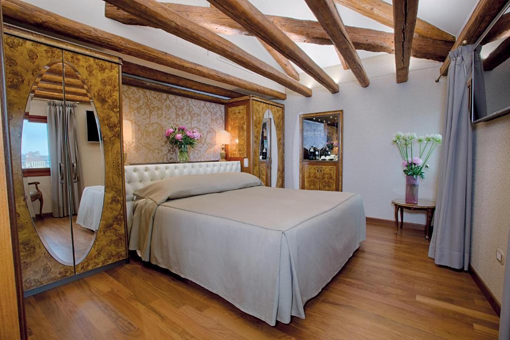a bedroom with a large bed and a mirror at Hotel Santa Chiara in Venice