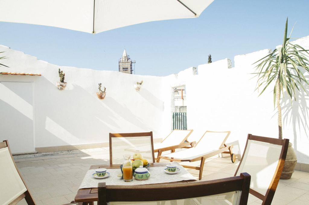 un patio con tavolo, sedie e parete bianca. di Palazzo Bianchi - Trani a Trani