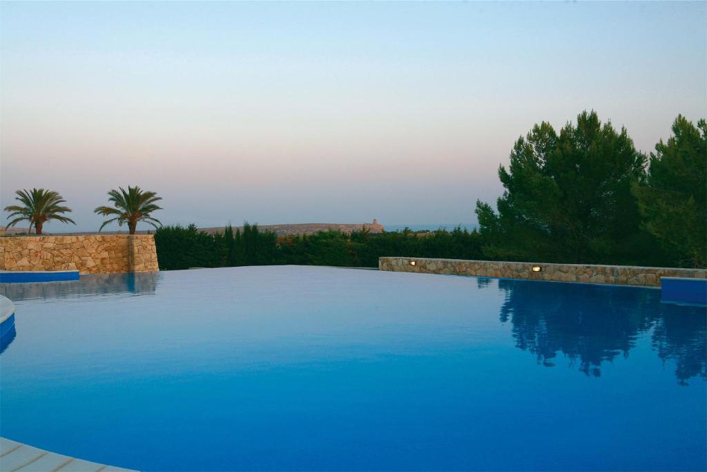 een groot blauw zwembad met bomen op de achtergrond bij Masseria Panareo in Otranto