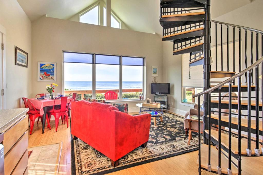 a living room with a red couch and a table at Oceanfront Cottage with Deck and Secluded Beach Access! in Yachats