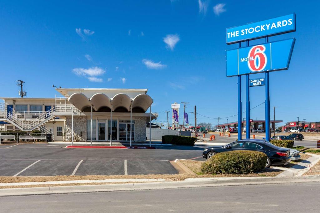 une voiture garée dans un parking en face d'un magasin dans l'établissement Motel 6 Fort Worth, Tx - Stockyards, à Fort Worth