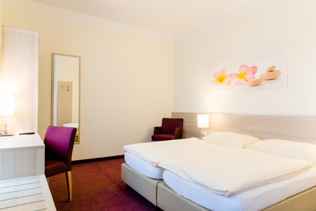 a bedroom with a bed and two chairs and a mirror at Hotel Pendl in Kalsdorf bei Graz