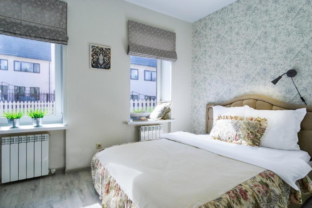 a bedroom with a bed and two windows at БЕСКОНТАКТНОЕ ЗАСЕЛЕНИЕ - GoldenRingApartments Super Central Location in Yaroslavl