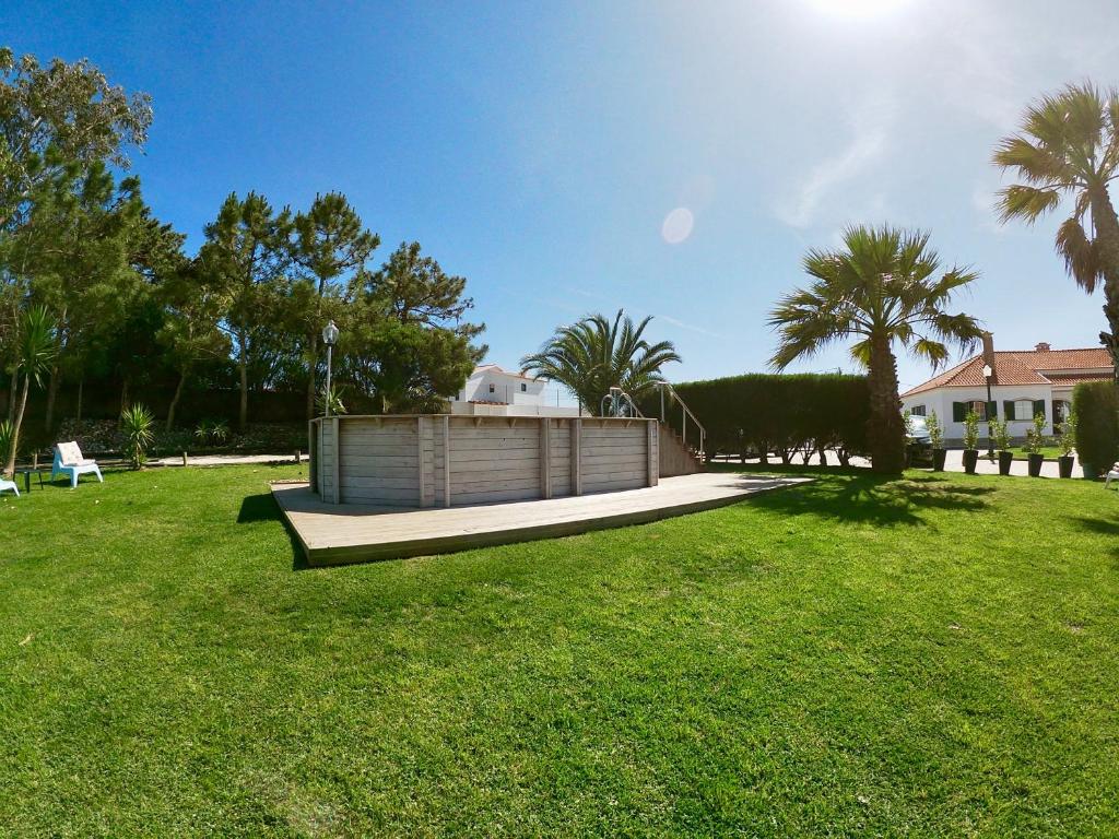 a green yard with a fence and palm trees at Golden Halcyon - Ericeira Villas in Ericeira
