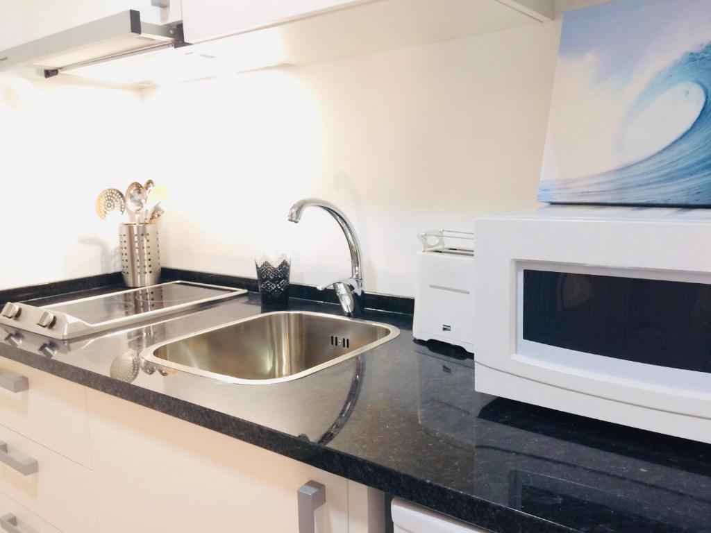 a kitchen with a sink and a microwave at Golden Halcyon - Ericeira Villas in Ericeira