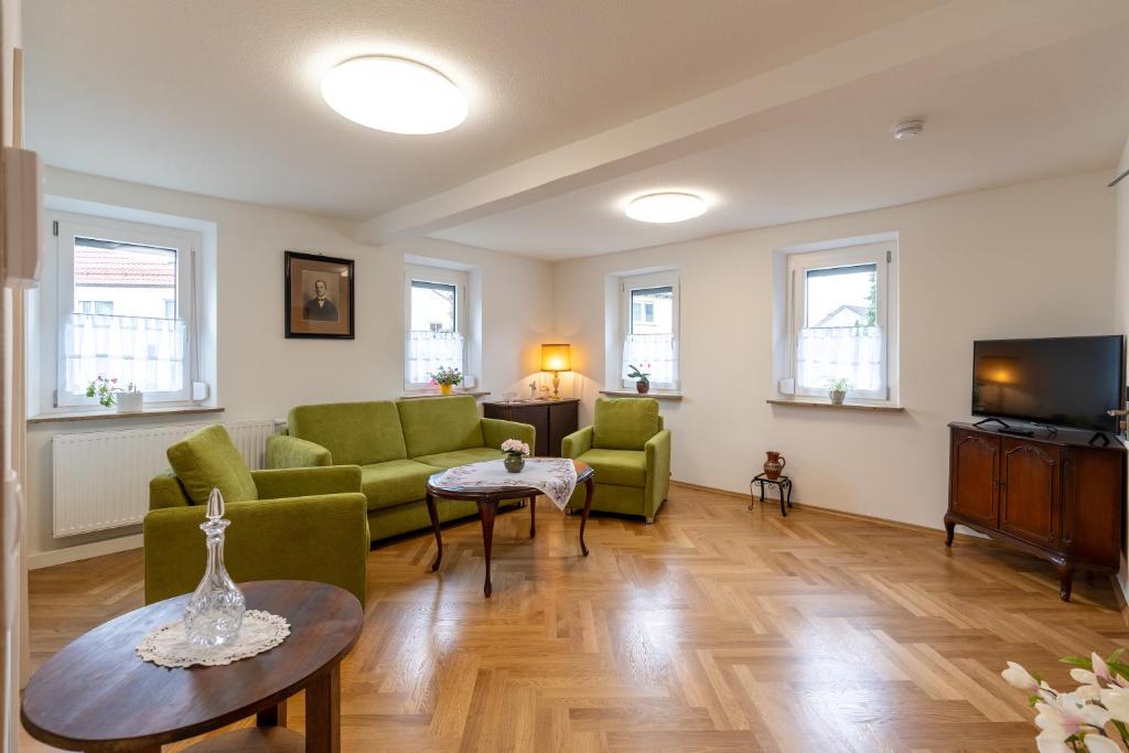 a living room with green chairs and a tv at Haus Burk 5.0 in Forchheim