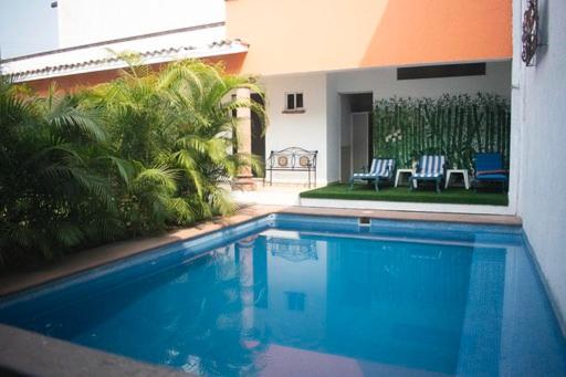a swimming pool in front of a house with two chairs at Villa Mont in Cuernavaca