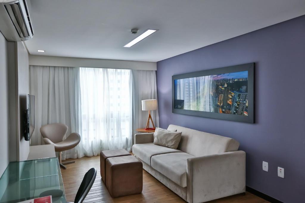 a living room with a couch and a tv on a wall at Roomo Praia de Boa Viagem Residencial in Recife