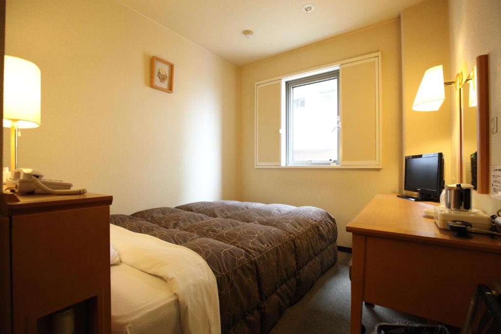um quarto de hotel com uma cama, uma secretária e uma janela em AZ Inn Obu em Obu
