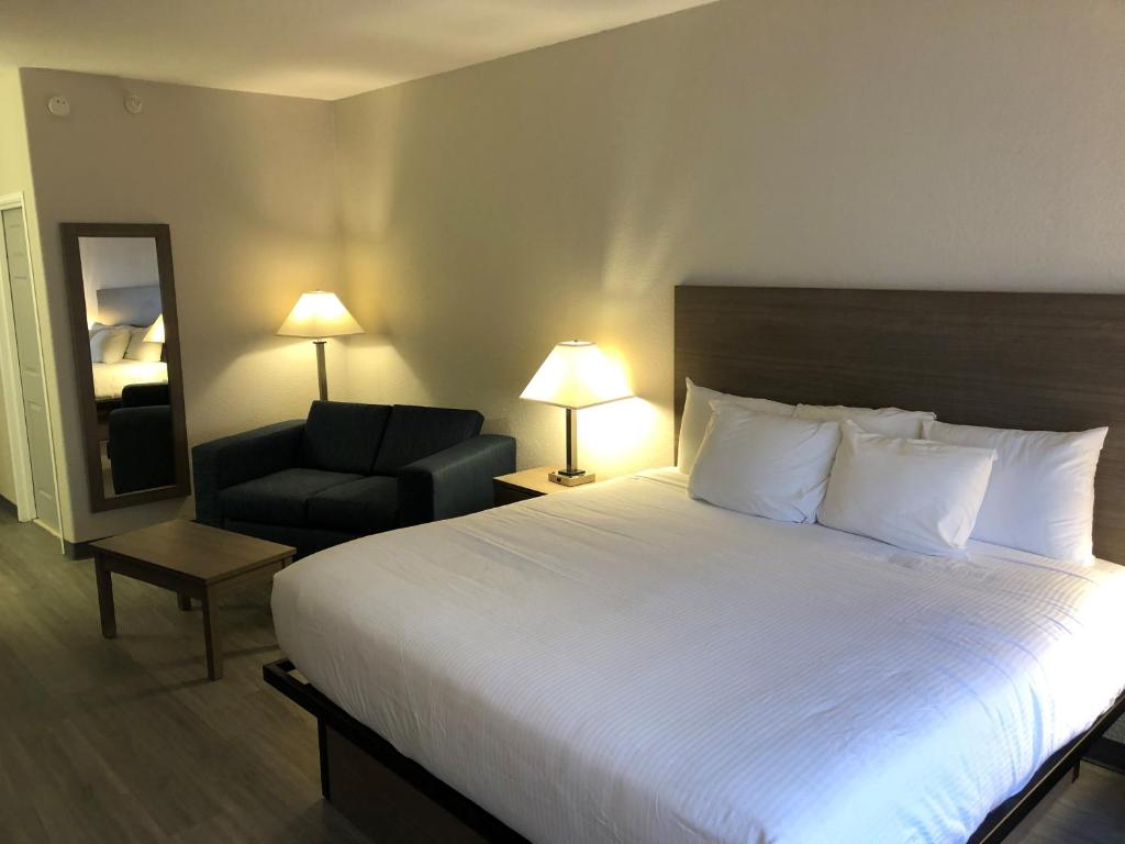 um quarto de hotel com uma cama grande e uma cadeira em GreenTree Inn Denver Tech Center em Centennial