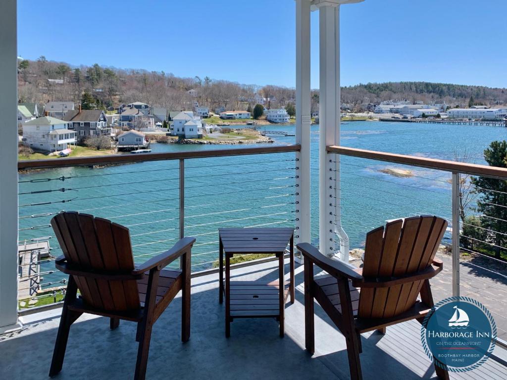 two chairs and a table on a balcony with a view of the water at Harborage Inn on the Oceanfront in Boothbay Harbor