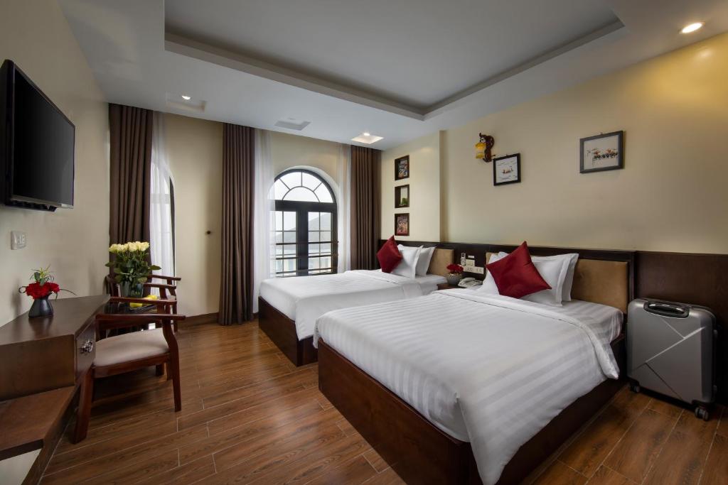 a hotel room with two beds and a television at Sapphire Sapa Hotel in Sapa