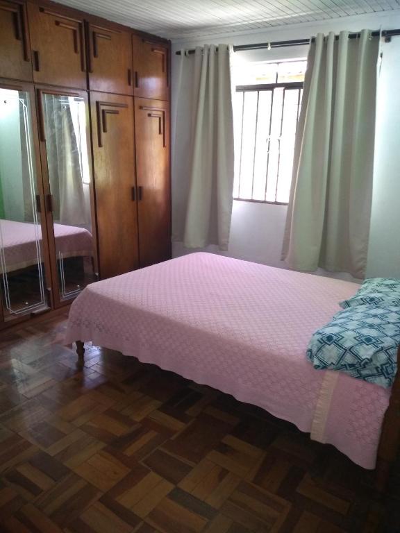 um quarto com uma cama com uma colcha rosa em Pousada Santa Felicidade, garagem T em Curitiba
