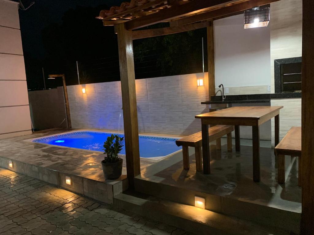 een patio met een tafel en 's avonds een zwembad bij Casa com piscina em c vermelha in Porto Seguro