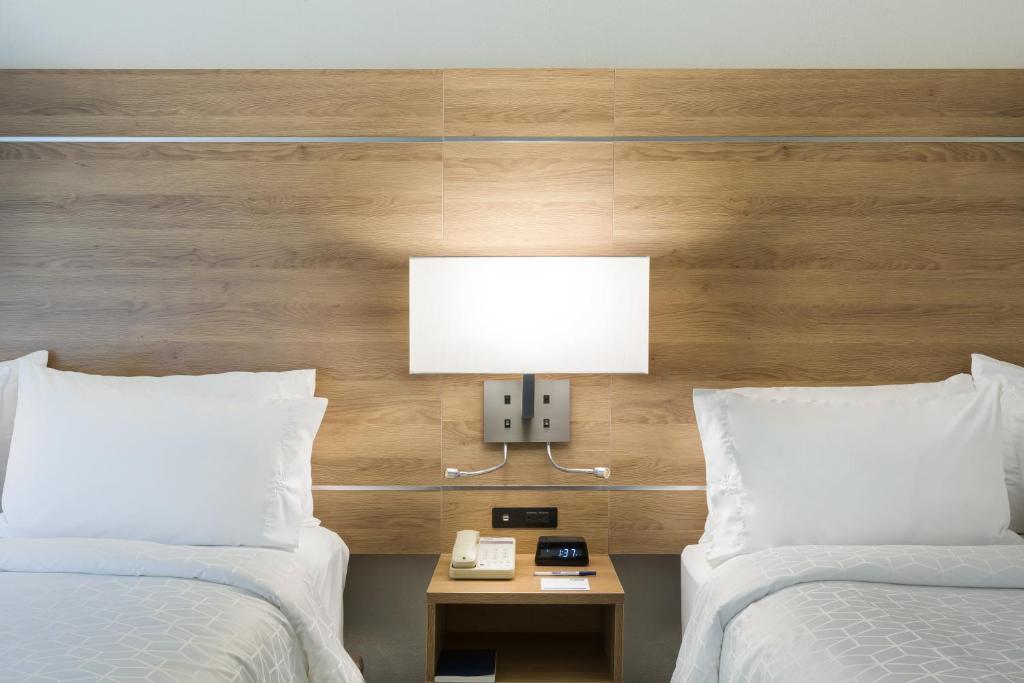 two beds in a hotel room with a lamp and a phone at Holiday Inn Express San Jose Costa Rica Airport by IHG in Alajuela City