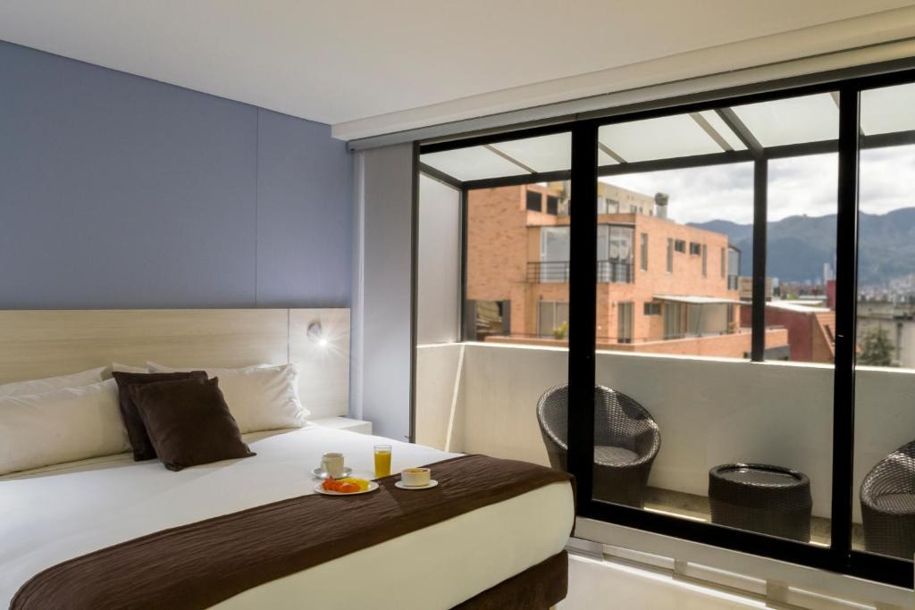 a bedroom with a bed and a large window at Hotel Regency Boutique La Feria in Bogotá
