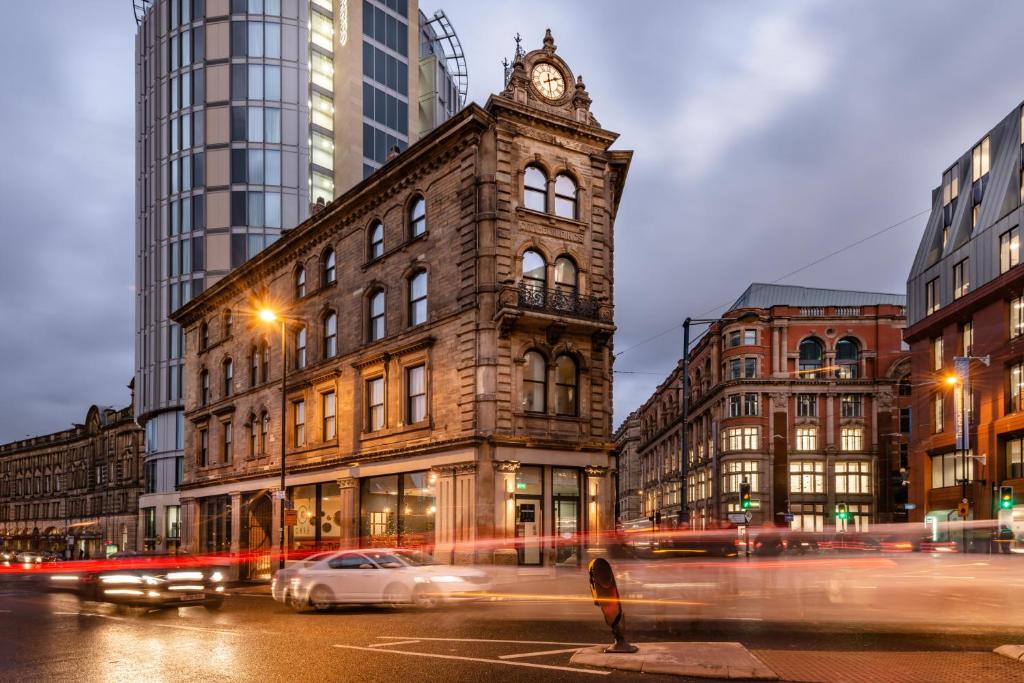 a city street at night with a clock tower at Hotel Indigo Manchester - Victoria Station, an IHG Hotel in Manchester