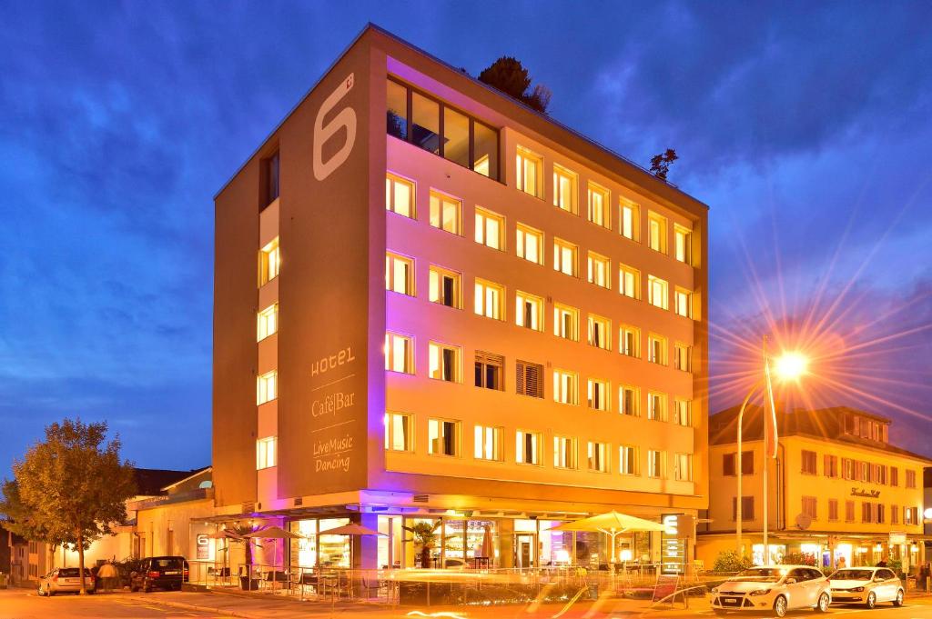 un grand bâtiment avec une lumière violette sur lui dans l'établissement Hotel SiX, à Kreuzlingen