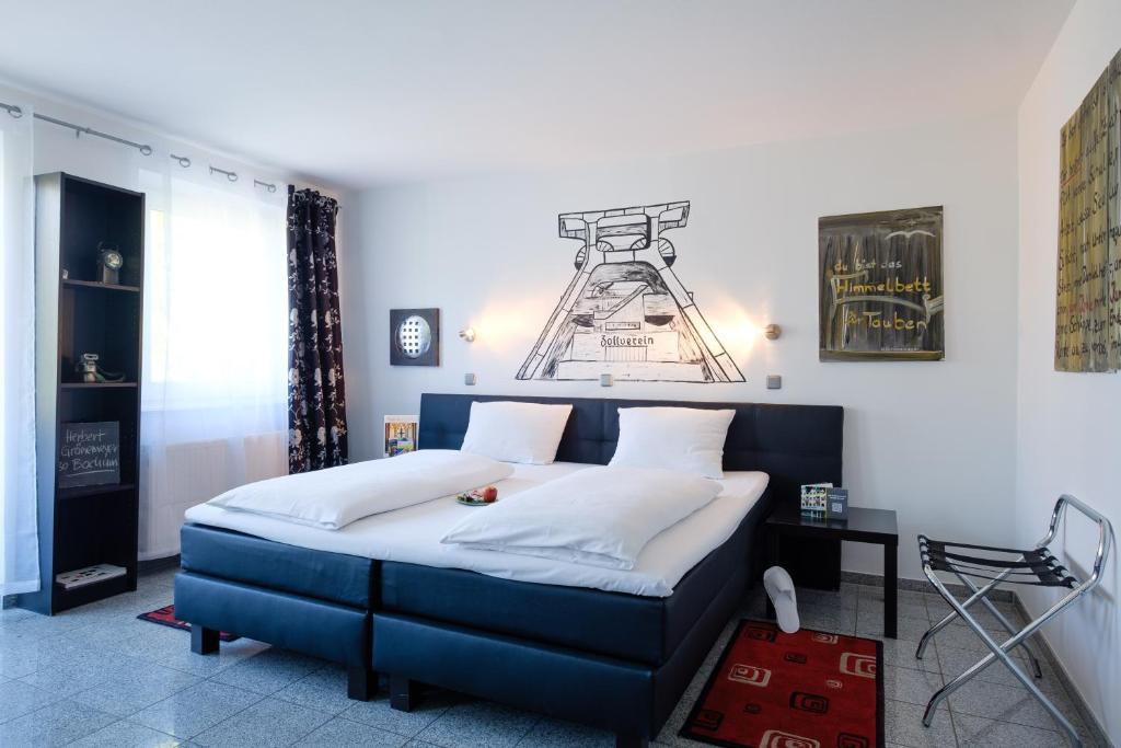 a bedroom with a blue bed with white pillows at art Hotel Körschen in Essen