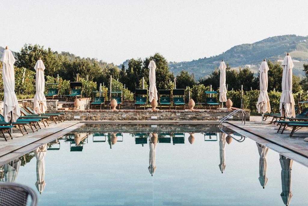 a swimming pool with umbrellas and chairs at Villa La Madonna in Monastero Bormida