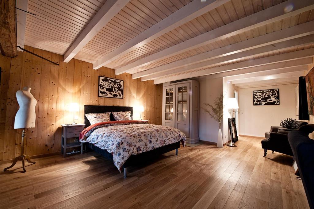 Les Arts Verts في Kruth: غرفة نوم بسرير وجدران خشبية وأرضيات خشبية