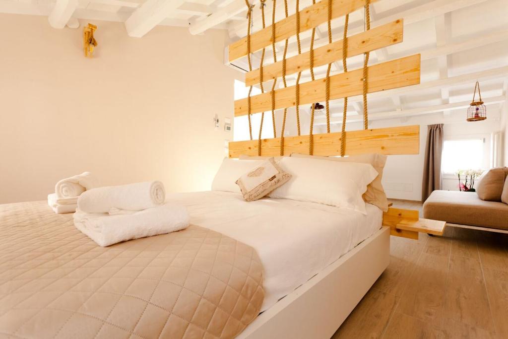 1 dormitorio con 1 cama grande con sábanas blancas en Colibrì house, en Sottomarina