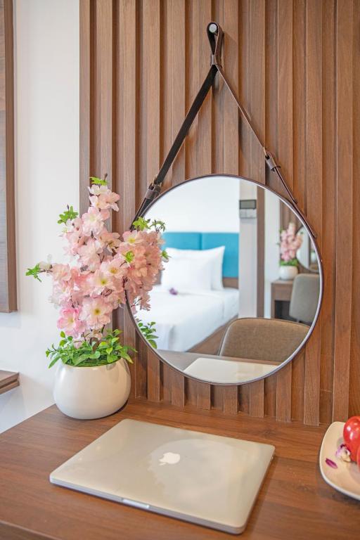 A compact in-room work surface with a laptop, round mirror and decorative flowers.