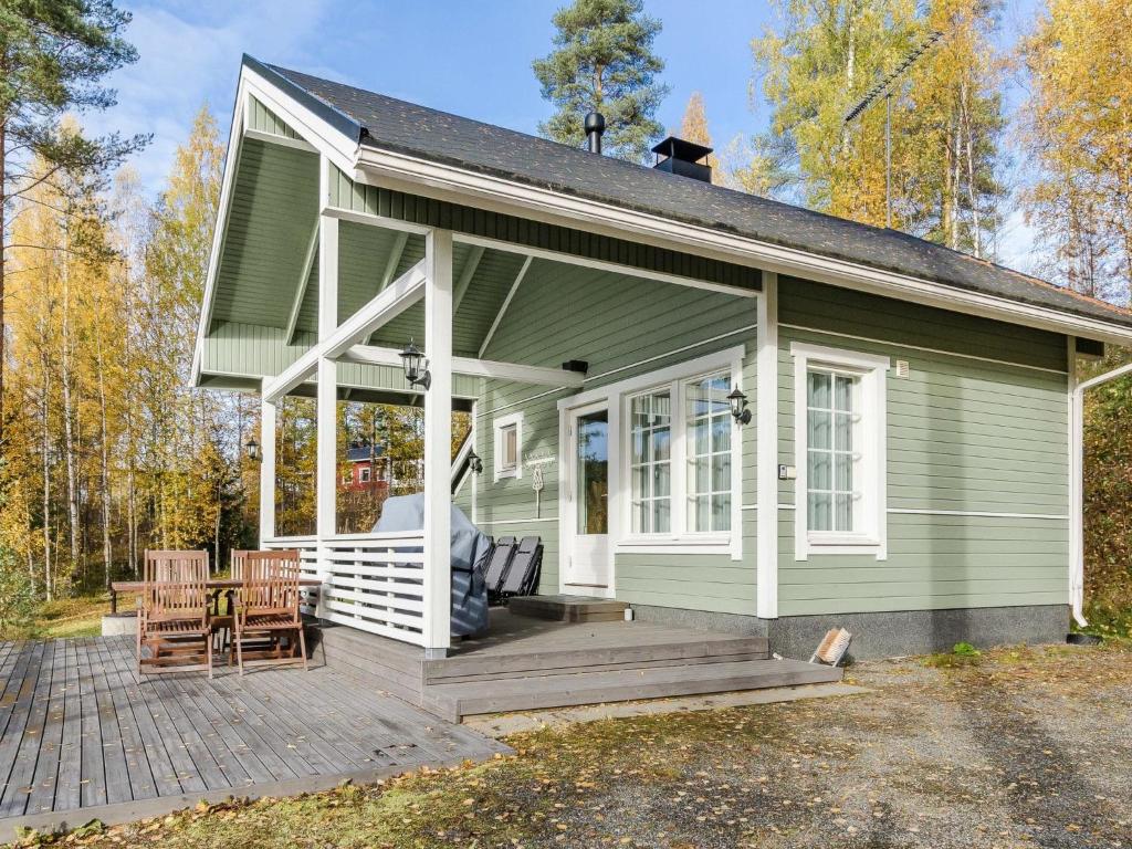 a green house with a porch and chairs on a deck at Holiday Home Pentintupa by Interhome in Muljakkala