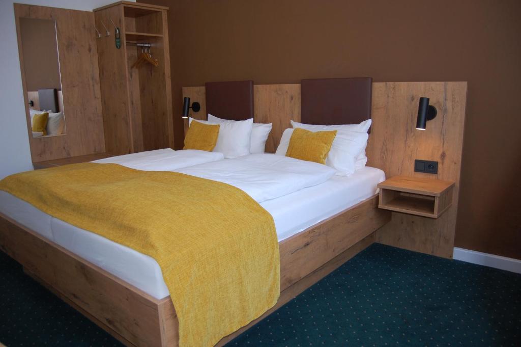 a bedroom with a large bed with a yellow blanket on it at Hotel Am Markt in Karlsruhe