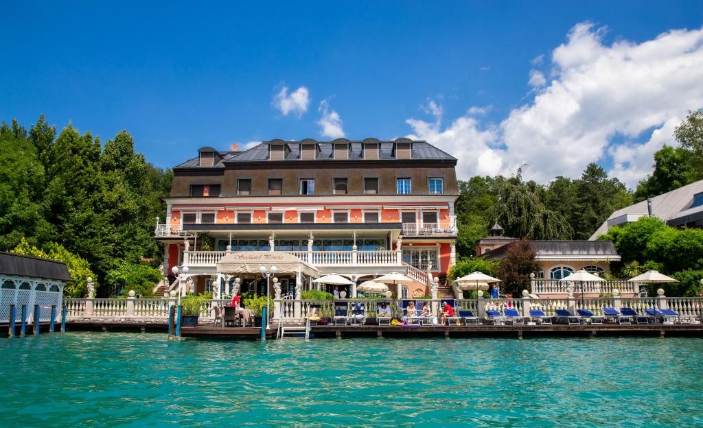 ein Hotel am Wasser neben einem Wasserkörper in der Unterkunft Seehotel Porcia in Pörtschach am Wörthersee