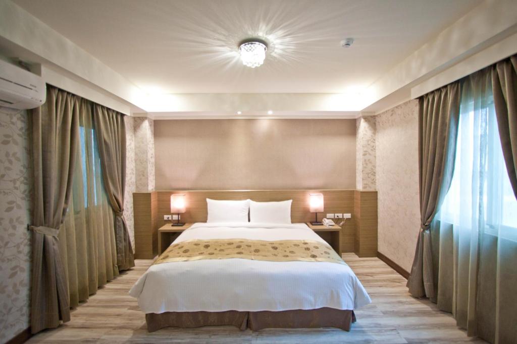 a bedroom with a large bed and two windows at True Friend Hotel in Hualien City