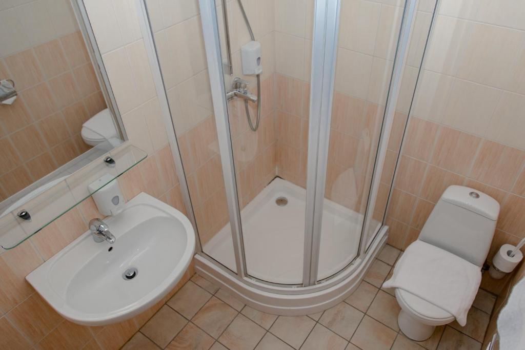 a bathroom with a shower and a sink and a toilet at Hotel Edvards in Rīga