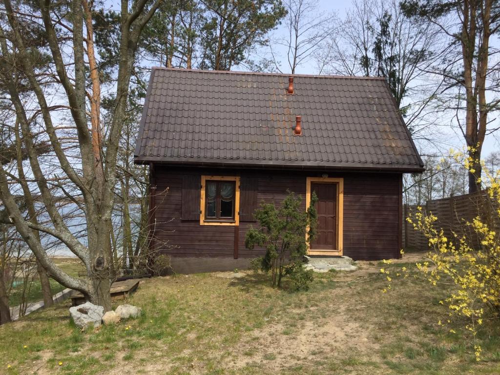 a small brown house with a black roof at Domek przy plaży in Narty