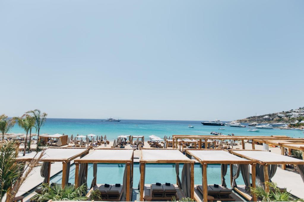 
a dining area with tables and chairs and umbrellas at Branco Mykonos in Platis Yialos Mykonos
