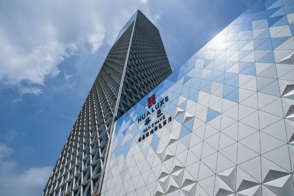 um edifício de vidro alto com um sinal nele em HUALUXE Hotels & Resorts Nanchang High-Tech Zone, an IHG Hotel em Nanchang