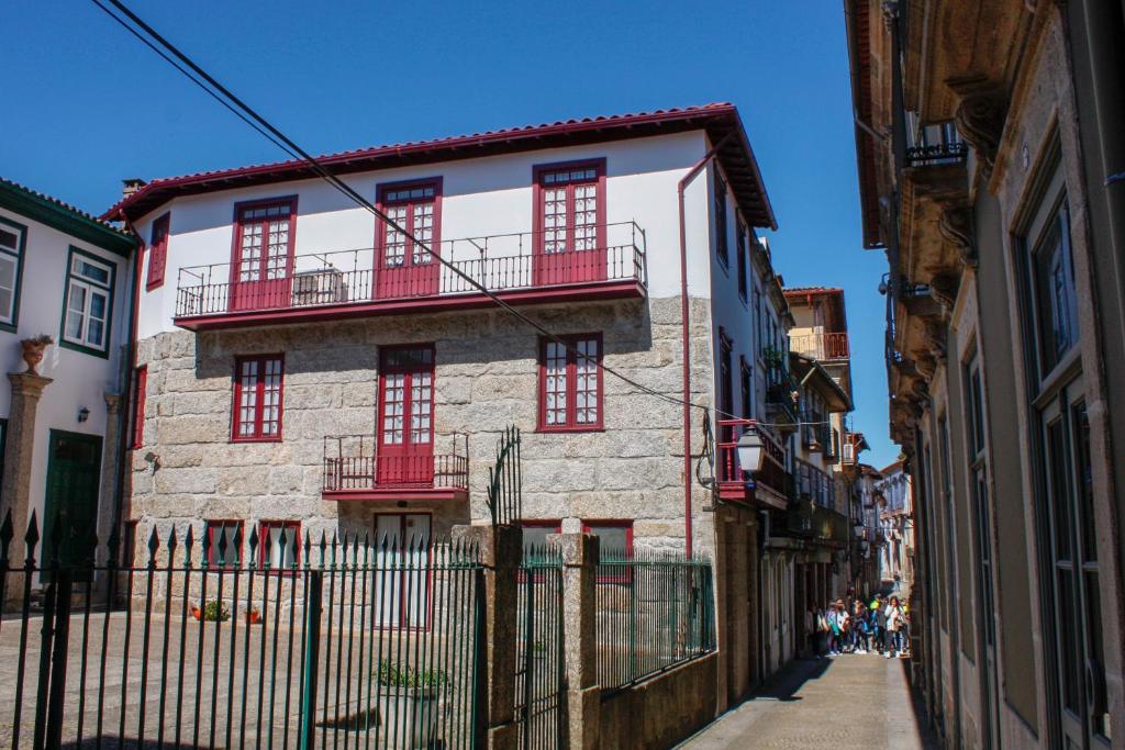 an old building with red windows on a street at Molarinho Heritage in Guimarães
