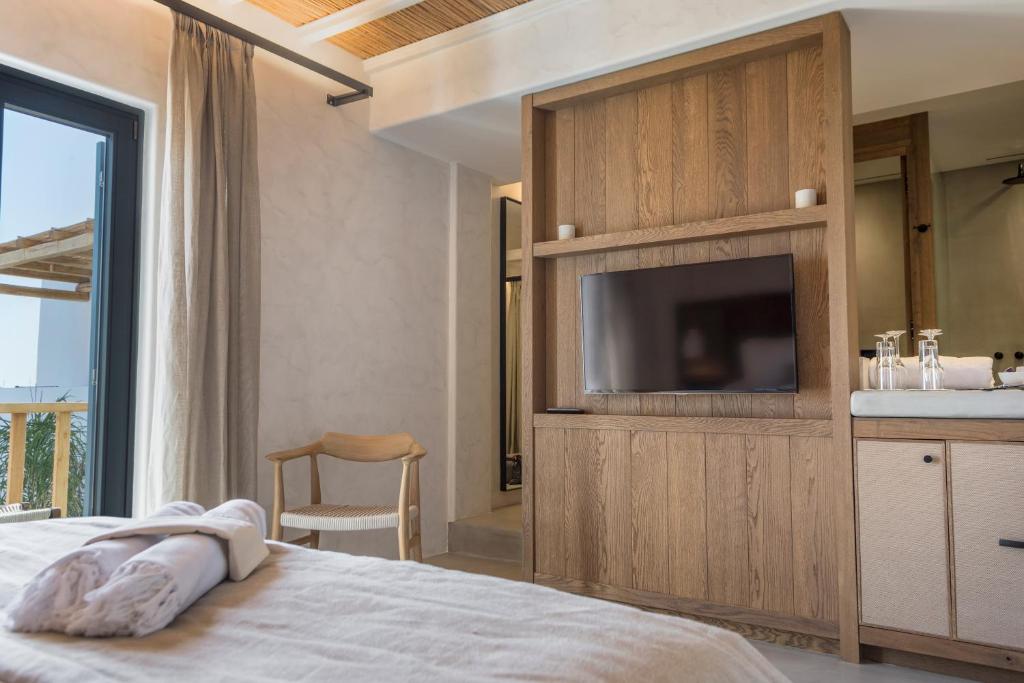 a bedroom with a bed with a television and a sink at Branco Mykonos in Platis Gialos