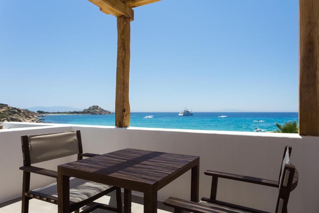 a wooden table and chairs on a balcony with the ocean at Branco Mykonos in Platis Gialos