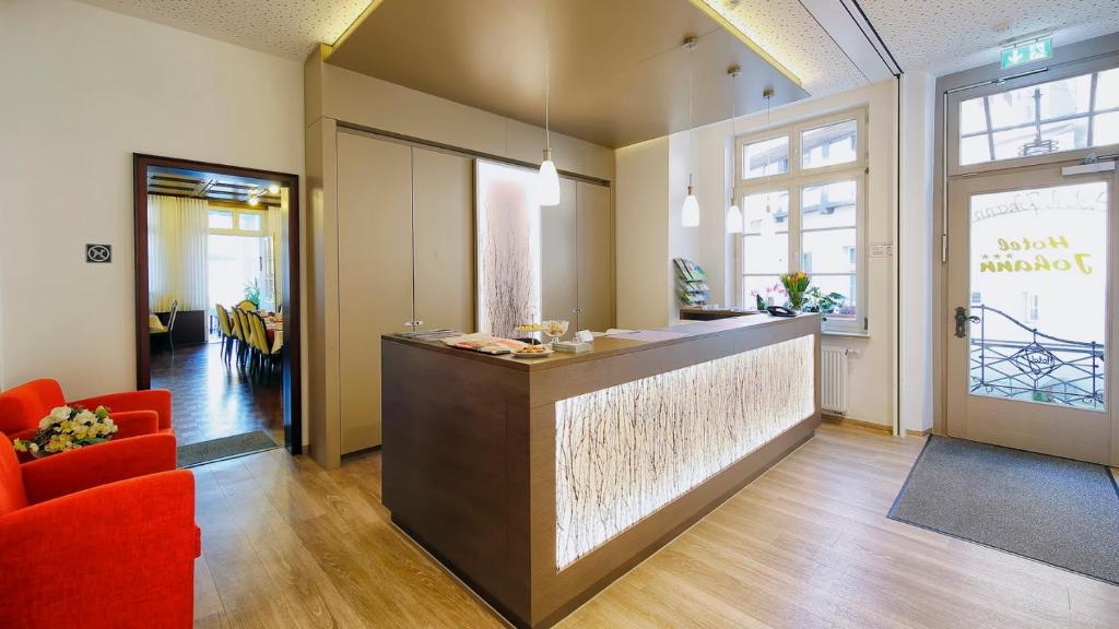 a lobby with a bar and red chairs in a room at Hotel Johann in Warendorf