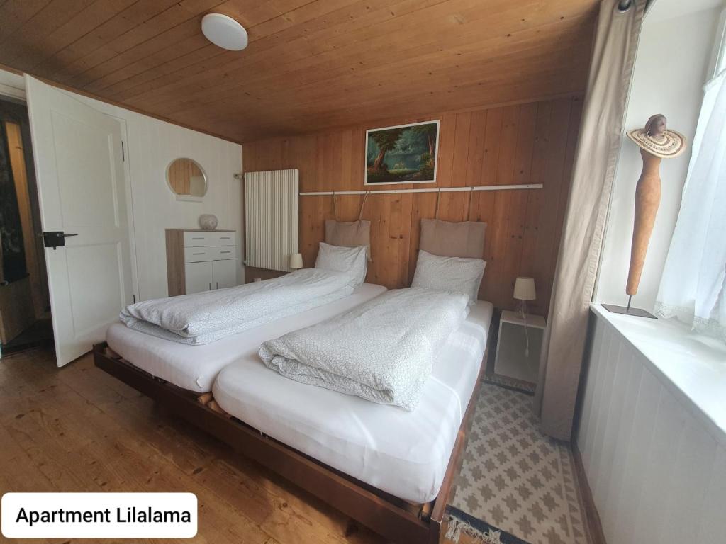 a bedroom with two beds in a wooden room at Apartment Lilalama in Grindelwald
