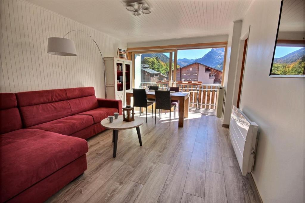 uma sala de estar com um sofá vermelho e uma mesa em APPARTEMENT LUMINEUX AVEC 2 BALCONS - MORZINE - 6 PERSONNES - NANTAUX 17 B em Morzine