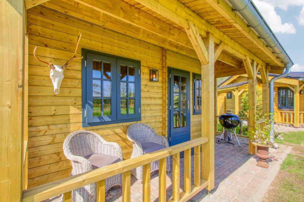 a cabin with a porch with chairs and a grill at Appel Lodge in Diessen