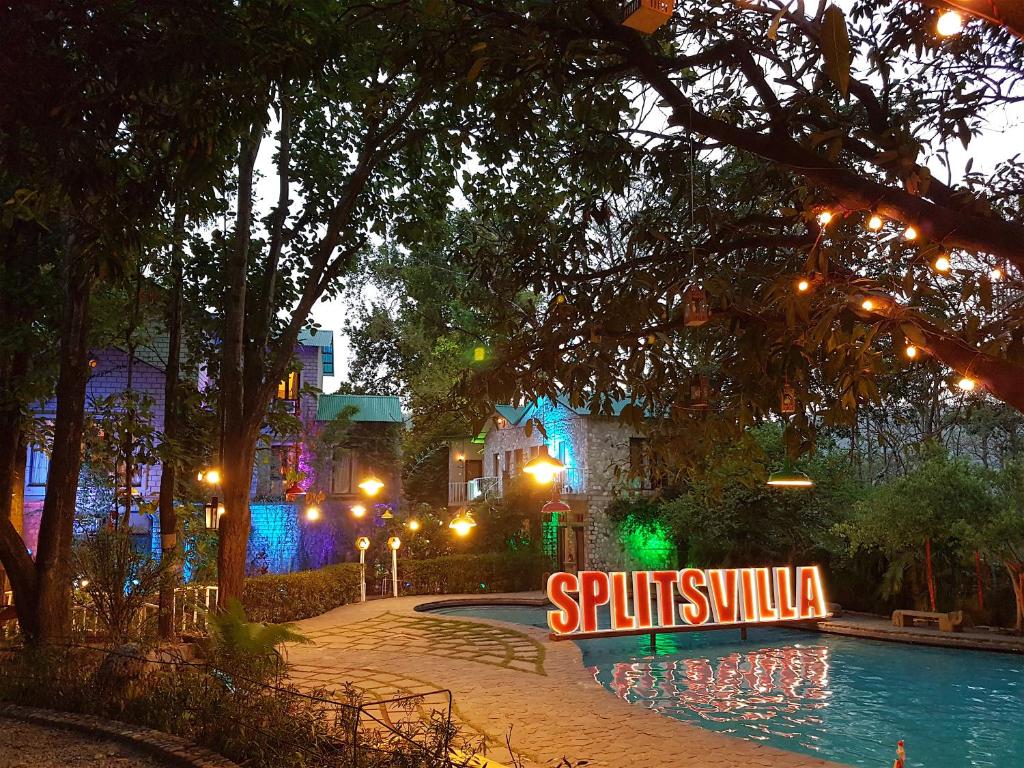 a swimming pool with a sign in front of a building at The Den Corbett Resort in Dhikala Zone