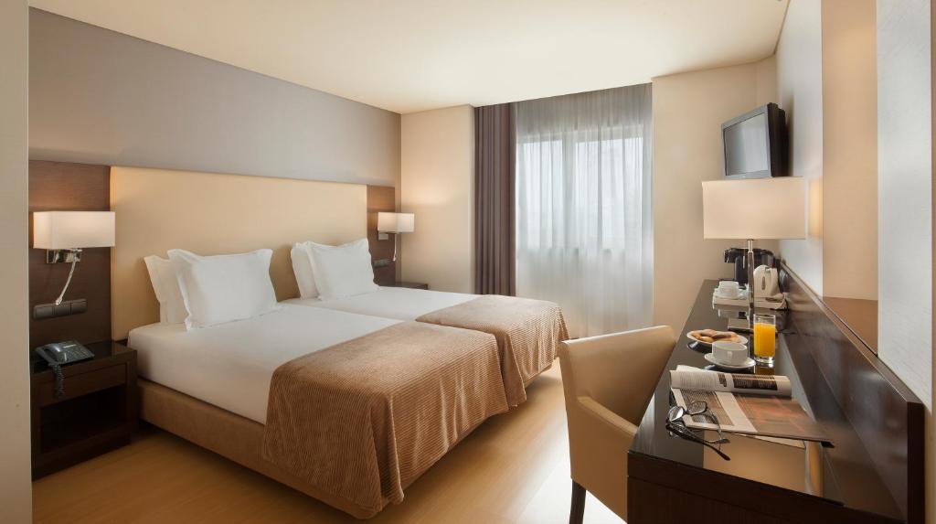 a hotel room with a bed and a desk at TURIM Ibéria Hotel in Lisbon