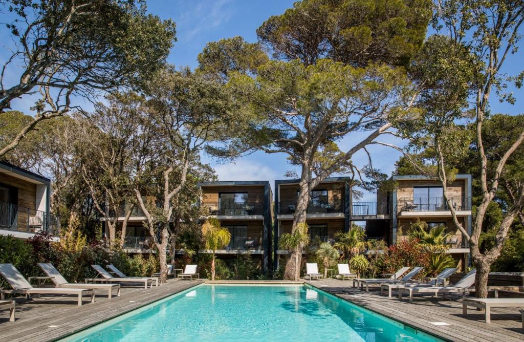 un immeuble d'appartements avec une piscine et des arbres dans l'établissement Le Lodge des Îles d'Or, à Hyères