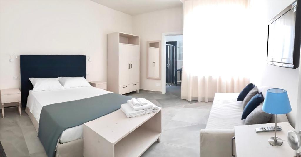 ein weißes Schlafzimmer mit einem großen Bett und einem Sofa in der Unterkunft B&B felix in Porto Cesareo