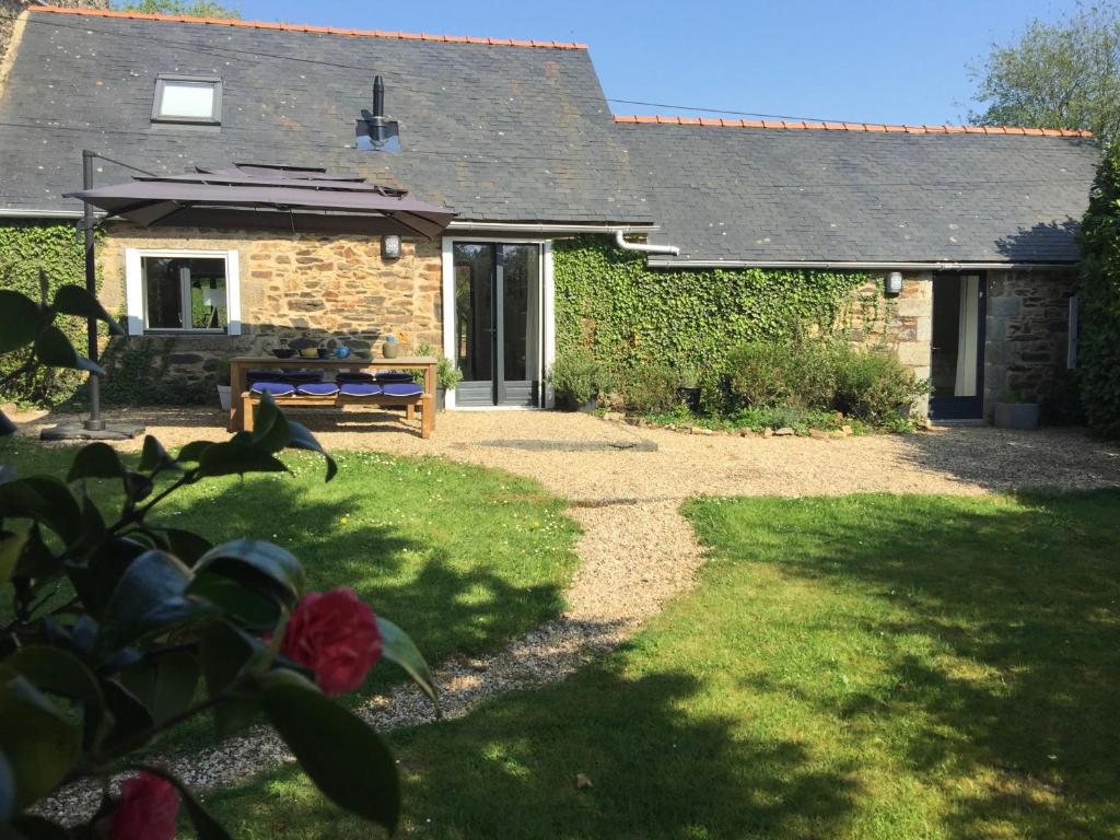 a stone house with a bench in the yard at La Colline des Renards in Locmaria-Berrien