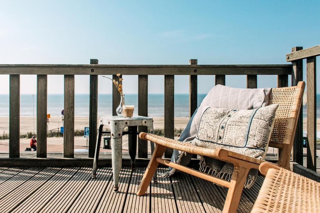 a chair and a table on a deck with the beach at Boulevard 5 in Zandvoort